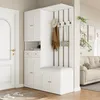 A white entryway storage set with a bench, coat hooks, and cabinets, placed next to a white door and in front of a living room with a sofa. Anteprima dell’immagine prodotto