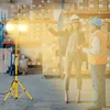 Two people in a warehouse setting, one pointing and the other holding a tablet, with a work light in the foreground. Produktbild-Vorschau