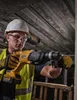 A construction worker is using a DeWALT hammer drill on a construction site. Produktbild-Vorschau