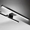 A close-up, angled view of a modern black LED light fixture with white light emanating from it, mounted above a reflective surface. Produktbild-Vorschau