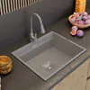 A modern kitchen sink with a gray faucet, set on a dark countertop with a bowl of figs and a wooden bowl nearby. Podgląd zdjęcia produktu