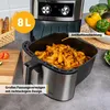 An air fryer filled with french fries, with some vegetables and bread in the background. Produktbild-Vorschau