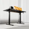 A black adjustable standing desk with orange accents and the text '70KG' on top, set against a white and light gray background with vertical blinds. Anteprima dell’immagine prodotto