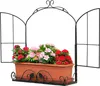 A black metal window frame with a brown planter filled with red and pink artificial flowers. Produktbild-Vorschau