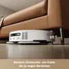 A robot vacuum cleaner is shown cleaning under a brown leather sofa, with a measurement indicating the clearance height. Produktbild-Vorschau