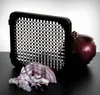 A red onion and chopped red onion are placed next to a black onion/vegetable dicer with a checkered pattern on its blades. Náhled obrázku produktu