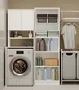 A laundry room with a washing machine, shelves filled with laundry supplies, and a clothes rack. Produktbild-Vorschau