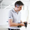 A man in a workshop holding a cordless drill. Voir les images du produit