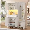 A white entryway storage unit with multiple compartments, drawers, a bench, a mirror, and hooks, set against a blurred background of a room interior and an outdoor view. Produktbild-Vorschau