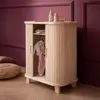 A wooden doll wardrobe with sliding doors, containing doll clothes, set against a purple wall and wooden floor. Produktbild-Vorschau