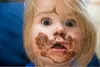 A close-up of a young child's face covered in chocolate. Produktbild-Vorschau
