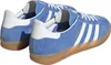 A pair of blue Adidas Gazelle Indoor sneakers with white stripes and a tan sole, shown from a side-rear angle on a white background. Produktbild-Vorschau