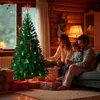 A family is gathered around a decorated Christmas tree, with presents underneath, in a cozy, wood-paneled room. Produktbild-Vorschau
