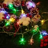 A close-up of a Christmas wreath decorated with pine cones, cotton balls, red berries, and snowflake-shaped LED lights. Produktbild-Vorschau