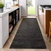 A dark grey runner rug is placed on a wooden floor in a kitchen or hallway, between a white counter and a wooden cabinet. Produktbild-Vorschau