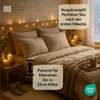 A cozy bedroom scene with a bed made with neutral-toned bedding, decorated with string lights and candles. Produktbild-Vorschau