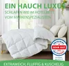 A neatly folded white comforter is displayed on a bed with several pillows, set against a bright window. Produktbild-Vorschau