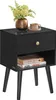 A black nightstand with a drawer and an open shelf, decorated with a vase of flowers and a cup of coffee on top. Produktbild-Vorschau