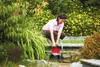 A woman is using a submersible pump in a garden pond. Náhled obrázku produktu