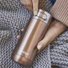 Hands holding a rose gold Contigo travel mug over a grey knitted blanket. Produktbild-Vorschau