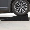 A car tire rests on a black plastic car ramp. Podgląd zdjęcia produktu