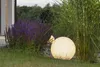 A garden scene at dusk with a large illuminated sphere light and purple flowers. Anteprima dell’immagine prodotto