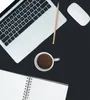 A flat lay of a laptop, coffee cup, pencil, mouse, and notebook on a black surface. Produktbild-Vorschau