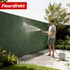 A man is cleaning a green fence with a hose in a garden. Anteprima dell’immagine prodotto