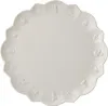 A white scalloped plate with embossed festive figures around the rim. Produktbild-Vorschau