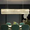 A rectangular crystal chandelier hangs above a dining table with green chairs. Náhľad obrázku produktu