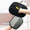 A hand is shown wearing a black pet grooming glove, with a yellow tab sticking out. Below it, another hand is shown wearing a gray glove. Produktbild-Vorschau