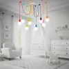 A nursery room with a crib, armchair, and a colorful chandelier. Anteprima dell’immagine prodotto