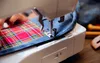 Close-up of a sewing machine stitching two pieces of fabric together. Produktbild-Vorschau