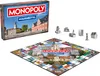 A Monopoly board game box and board are displayed, along with game pieces. Produktbild-Vorschau