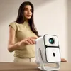 A woman is interacting with a white projector on a table. Produktbild-Vorschau