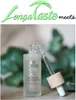 A bottle of anti-aging serum with a dropper, set against a soft green and beige background with blurred foliage. Náhľad obrázku produktu