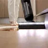 A person is using a wet and dry vacuum cleaner to clean a spill on a wooden floor. Náhled obrázku produktu