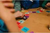 People playing a card game at a wooden table. Produktbild-Vorschau