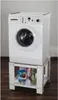 A white washing machine is placed on a white stand with storage shelves below. Laundry detergent and other cleaning products are visible on the shelves. Náhled obrázku produktu