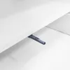 A close-up view of a gray plastic push-to-open latch mechanism attached to the underside of a white shelf or table. Voir les images du produit