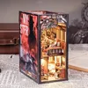 A miniature diorama of a train compartment, designed to fit between books on a shelf, with a detailed interior and exterior. Voir les images du produit