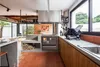 A modern kitchen with a wood-burning stove as the central feature, surrounded by concrete countertops and wooden cabinets. Produktbild-Vorschau