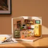 A miniature dollhouse kitchen scene with a yellow refrigerator, stove, sink, and dining table. Podgląd zdjęcia produktu