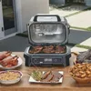 An outdoor setting with a grill and various cooked foods. Voir les images du produit