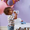 A young child drinks from a bottle while sitting at a table with a snack bowl. Náhled obrázku produktu