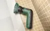 A Bosch electric cleaning brush with green bristles is shown resting on the edge of a bathtub, with water droplets on its surface, next to a tiled wall. Voir les images du produit