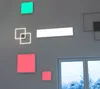 Several illuminated geometric shapes are mounted on a gray wall next to a window. Produktbild-Vorschau