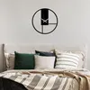 A modern wall clock is mounted on a textured wall above a bed with several pillows and a striped blanket. Podgląd zdjęcia produktu