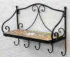 A black metal wall shelf with a mosaic tile surface and hooks underneath, mounted on a textured white wall. Podgląd zdjęcia produktu