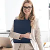 A woman in a business suit holds a navy blue laptop bag in an office setting. Anteprima dell’immagine prodotto